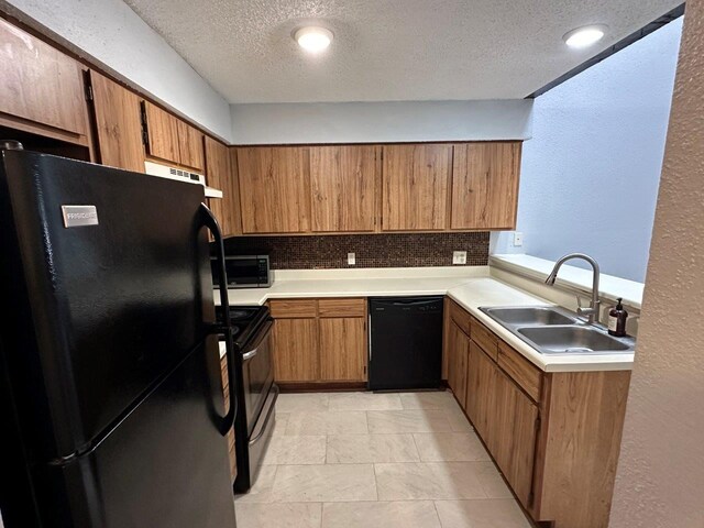 2510 Grants Lake Blvd Unit 101, Sugar Land, TX 77479 - kitchen with black appliances, a textured ceiling, tasteful backsplash, brown cabinets, and light countertops