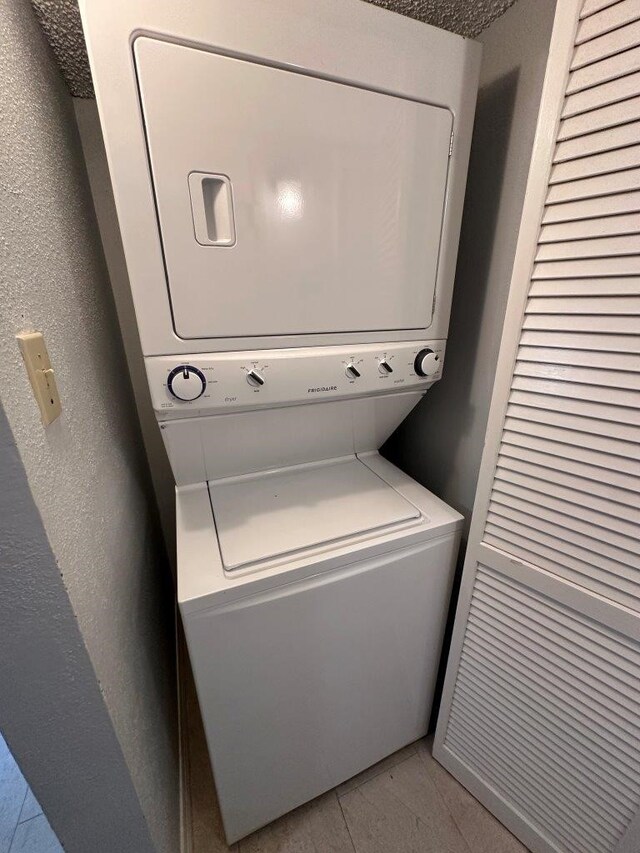 2510 Grants Lake Blvd Unit 101, Sugar Land, TX 77479 - laundry room featuring stacked washer and clothes dryer and light tile patterned floors