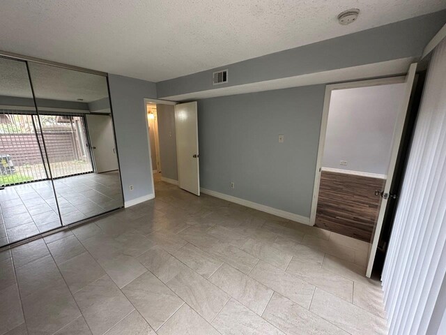 2510 Grants Lake Blvd Unit 101, Sugar Land, TX 77479 - unfurnished bedroom with a textured ceiling, access to exterior, and tile patterned floors