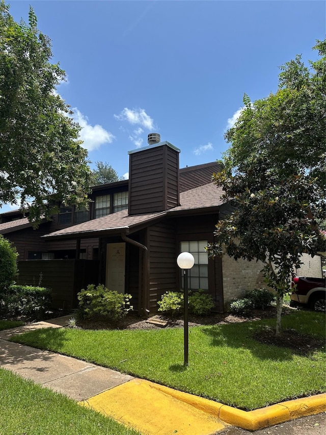 2510 Grants Lake Blvd Unit 101, Sugar Land, TX 77479 - view of front facade featuring a front lawn, a chimney, a shingled roof, and brick siding