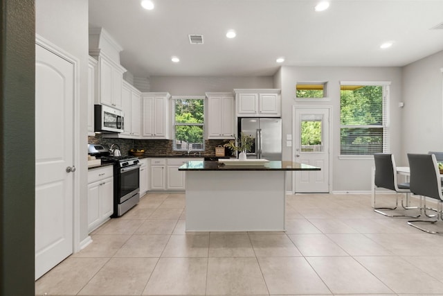 134 Biltmore Loop, Montgomery, TX 77316 - kitchen featuring stainless steel appliances, backsplash, a center island, white cabinetry, and recessed lighting