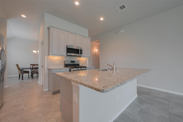 8326 Erasmus Landing Ct, Houston, TX 77044 - kitchen with stainless steel appliances, backsplash, light stone countertops, recessed lighting, and a center island with sink