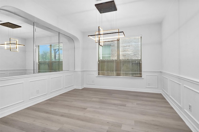 8422 Misty Mountain Trail Ln, Spring, TX 77389 - unfurnished dining area featuring a chandelier, a decorative wall, wainscoting, and wood finished floors