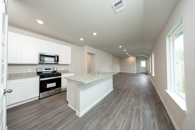 2569 Hawks Eye Dr, Conroe, TX 77301 - kitchen with stainless steel appliances, wood finished floors, white cabinetry, light stone counters, and recessed lighting