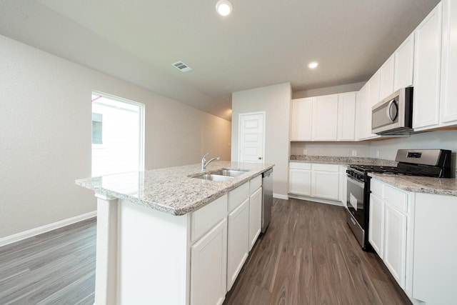 2569 Hawks Eye Dr, Conroe, TX 77301 - kitchen featuring appliances with stainless steel finishes, dark wood finished floors, light stone countertops, white cabinetry, and recessed lighting