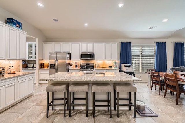24327 Hampton Terrace Ln, Spring, TX 77389 - kitchen featuring appliances with stainless steel finishes, vaulted ceiling, tasteful backsplash, a kitchen bar, and white cabinets