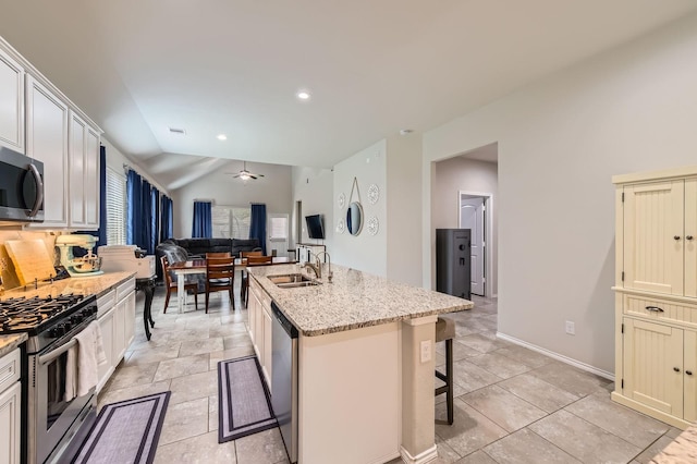 24327 Hampton Terrace Ln, Spring, TX 77389 - kitchen with stainless steel appliances, a breakfast bar area, open floor plan, an island with sink, and light stone countertops