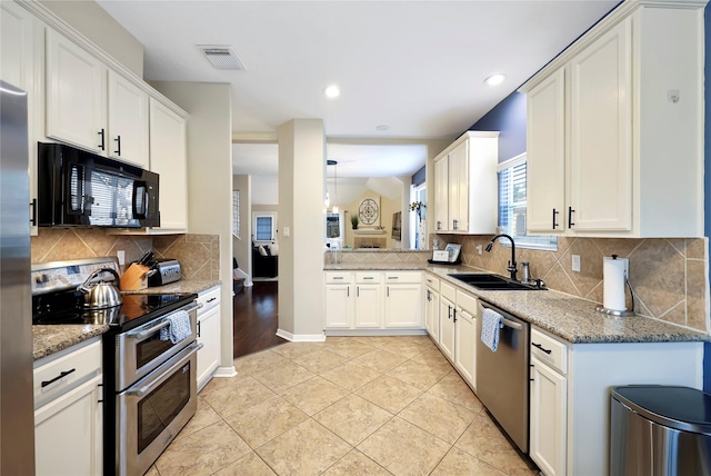 2818 Lake Forest Dr, Montgomery, TX 77356 - kitchen featuring appliances with stainless steel finishes, tasteful backsplash, light stone counters, light tile patterned flooring, and recessed lighting