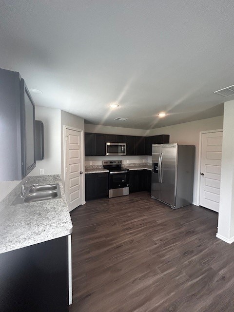 22919 Great Egret Dr, Splendora, TX 77372 - kitchen featuring appliances with stainless steel finishes, light countertops, dark wood-type flooring, and dark cabinets