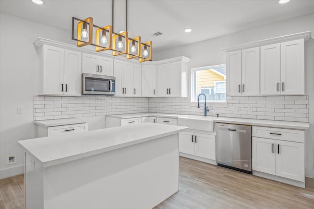 2015 Brackenridge St Unit B, Houston, TX 77026 - kitchen with stainless steel appliances, white cabinetry, recessed lighting, hanging light fixtures, and light wood-type flooring