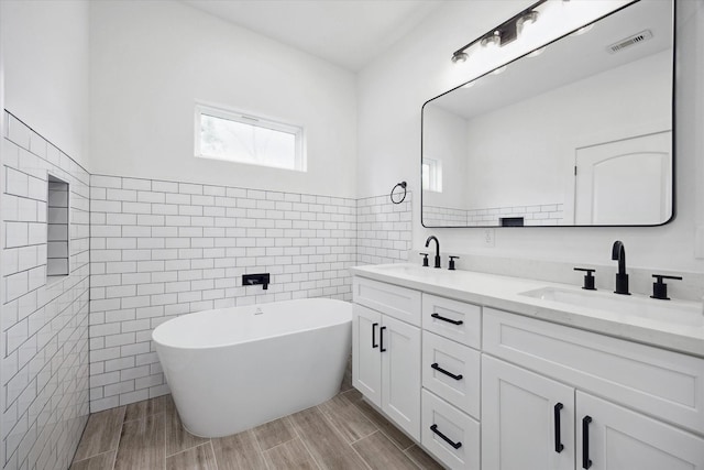 2015 Brackenridge St Unit B, Houston, TX 77026 - bathroom featuring tile walls, double vanity, a soaking tub, wood tiled floors, and a wainscoted wall
