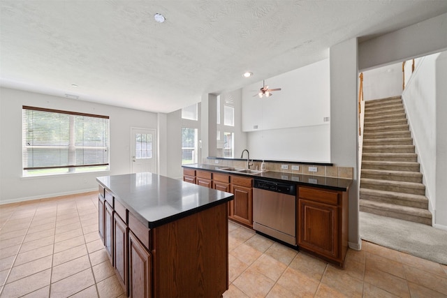 2022 Grand Willow Ln, Richmond, TX 77469 - kitchen with stainless steel dishwasher, light tile patterned floors, dark countertops, a center island, and ceiling fan