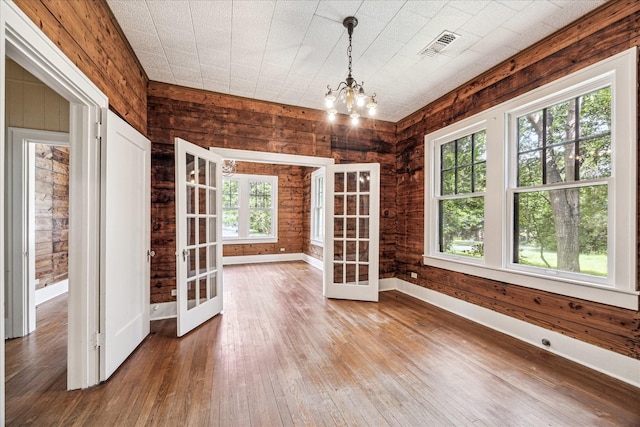 1407 S Baylor St, Brenham, TX 77833 - unfurnished dining area with french doors, hardwood / wood-style floors, a chandelier, and wood walls