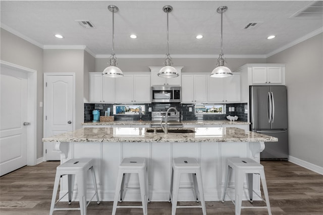 1790 Catfish Ln, Crystal Beach, TX 77650 - kitchen featuring appliances with stainless steel finishes, a center island with sink, a kitchen breakfast bar, white cabinetry, and decorative backsplash