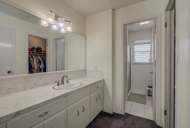 1120 Redfish St, Bayou Vista, TX 77563 - bathroom featuring vanity, a spacious closet, a textured ceiling, tile patterned flooring, and a stall shower