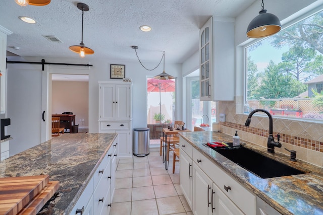 16322 Clearcrest Dr, Houston, TX 77059 - kitchen featuring a barn door, tasteful backsplash, light tile patterned flooring, glass insert cabinets, and white cabinetry