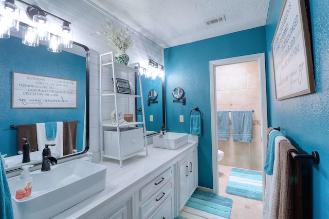 16322 Clearcrest Dr, Houston, TX 77059 - bathroom featuring a textured ceiling, a textured wall, double vanity, and tile patterned flooring