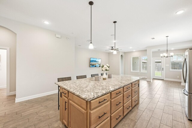 18314 Pedernales Springs Dr, Cypress, TX 77433 - kitchen with arched walkways, freestanding refrigerator, a kitchen island, light wood-style flooring, and decorative light fixtures