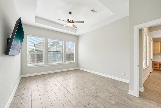 18314 Pedernales Springs Dr, Cypress, TX 77433 - empty room featuring a ceiling fan, a tray ceiling, healthy amount of natural light, and light wood-type flooring
