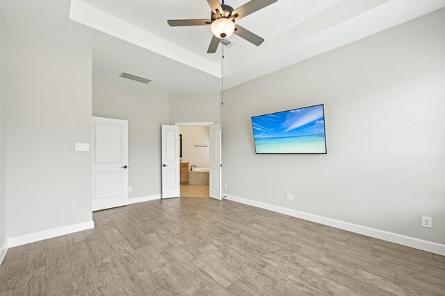 18314 Pedernales Springs Dr, Cypress, TX 77433 - unfurnished bedroom with wood finished floors, connected bathroom, a tray ceiling, and a ceiling fan