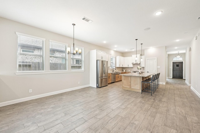 18314 Pedernales Springs Dr, Cypress, TX 77433 - kitchen with appliances with stainless steel finishes, light wood-style flooring, light countertops, a chandelier, and a kitchen bar