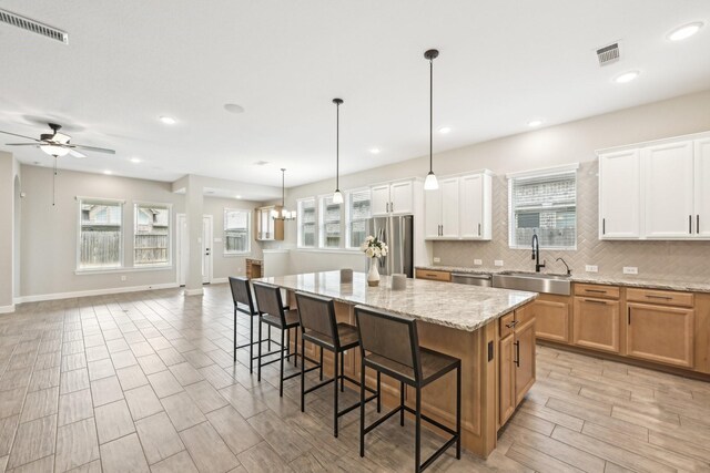 18314 Pedernales Springs Dr, Cypress, TX 77433 - kitchen with appliances with stainless steel finishes, a center island, tasteful backsplash, a ceiling fan, and a kitchen breakfast bar