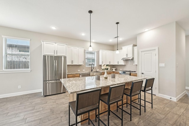 18314 Pedernales Springs Dr, Cypress, TX 77433 - kitchen with appliances with stainless steel finishes, light wood finished floors, under cabinet range hood, white cabinets, and recessed lighting