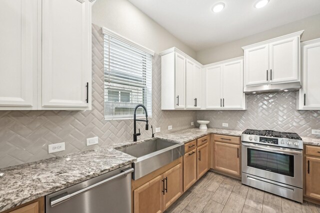 18314 Pedernales Springs Dr, Cypress, TX 77433 - kitchen featuring stainless steel appliances, decorative backsplash, light stone countertops, under cabinet range hood, and recessed lighting