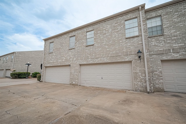 4001 Tanglewilde St Unit 1402, Houston, TX 77063 - view of property exterior featuring an attached garage, concrete driveway, and brick siding