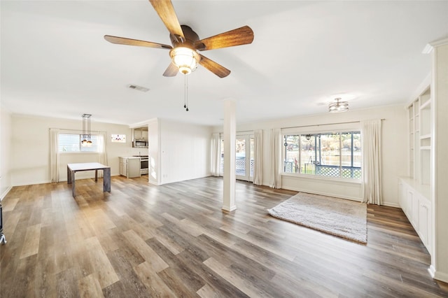 13318 Southshore Dr, Conroe, TX 77304 - unfurnished living room with plenty of natural light, a ceiling fan, wood finished floors, and ornate columns