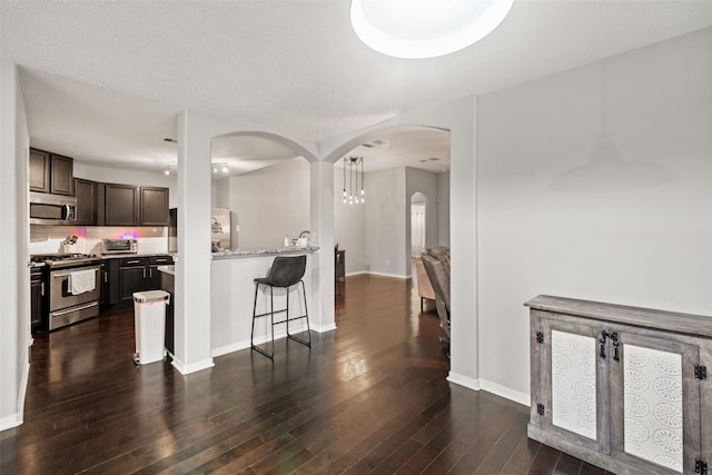 5726 Straight Way, Houston, TX 77339 - kitchen with appliances with stainless steel finishes, arched walkways, dark wood finished floors, dark brown cabinets, and a kitchen bar