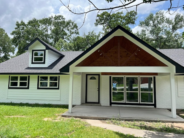 25907 Maplewood Dr, Spring, TX 77386 - view of front facade with a front yard, brick siding, roof with shingles, and a porch