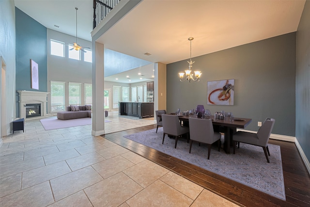 10022 Foggy Riv, Missouri City, TX 77459 - tiled dining space with a chandelier, a glass covered fireplace, a towering ceiling, and ceiling fan