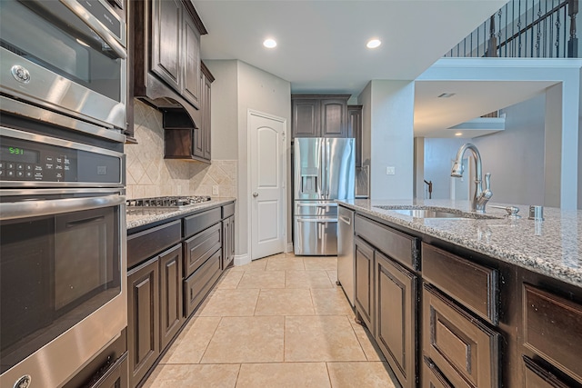 10022 Foggy Riv, Missouri City, TX 77459 - kitchen with stainless steel appliances, light stone countertops, backsplash, dark brown cabinets, and recessed lighting