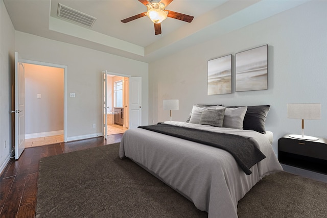 10022 Foggy Riv, Missouri City, TX 77459 - bedroom featuring a raised ceiling, dark wood-style floors, ensuite bath, and a ceiling fan