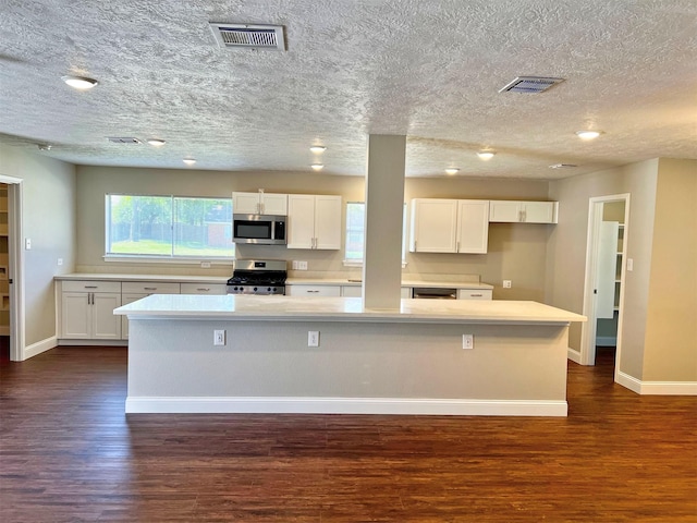 415 Sevenhampton Ln, Houston, TX 77015 - kitchen with stainless steel appliances, dark wood-style flooring, white cabinets, plenty of natural light, and a textured ceiling