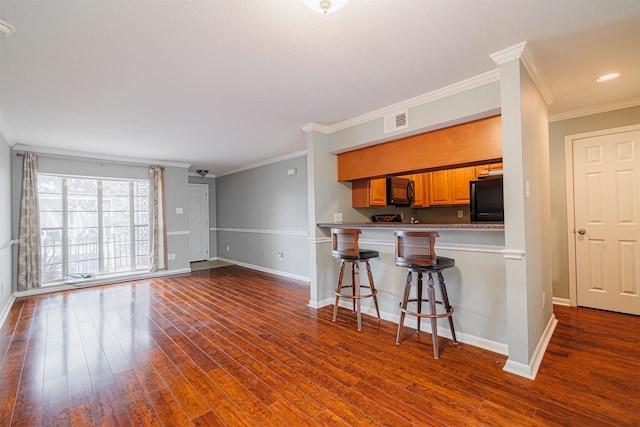 2621 Marilee Ln Unit 3, Houston, TX 77057 - kitchen with black appliances, dark wood-style floors, ornamental molding, light countertops, and a kitchen breakfast bar