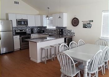 1310 Seashell Dr, Surfside Beach, TX 77541 - kitchen featuring stainless steel appliances, decorative backsplash, a peninsula, dark wood finished floors, and lofted ceiling
