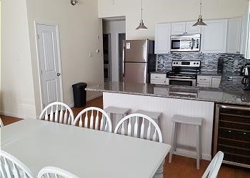 1310 Seashell Dr, Surfside Beach, TX 77541 - kitchen with stainless steel appliances, wine cooler, decorative backsplash, a peninsula, and white cabinets