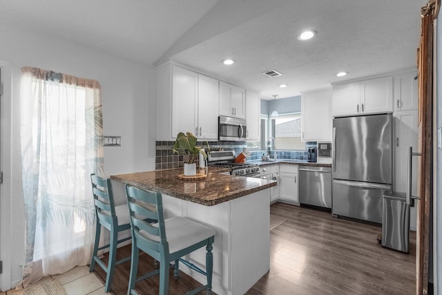 253 Barracuda St, Bayou Vista, TX 77563 - kitchen with appliances with stainless steel finishes, a peninsula, white cabinets, decorative backsplash, and recessed lighting