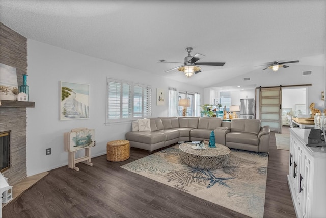 253 Barracuda St, Bayou Vista, TX 77563 - living area featuring a barn door, ceiling fan, lofted ceiling, dark wood-type flooring, and a stone fireplace