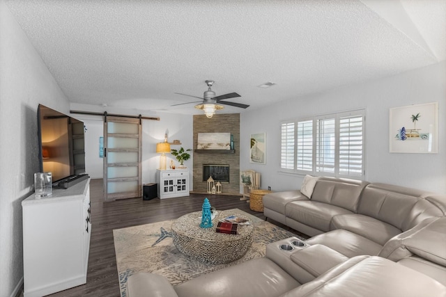 253 Barracuda St, Bayou Vista, TX 77563 - living room featuring a barn door, a textured ceiling, ceiling fan, dark wood-type flooring, and a fireplace