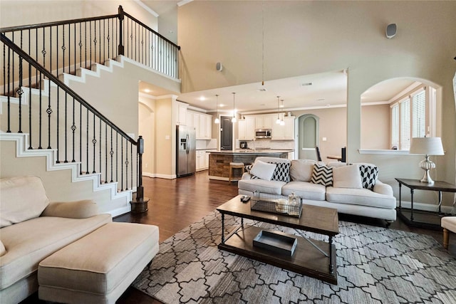 17522 Mineral Bluff Ln, Humble, TX 77346 - living room featuring arched walkways, ornamental molding, dark wood-style floors, a towering ceiling, and stairs