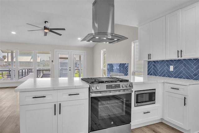 38 N Flamingo St, La Marque, TX 77568 - kitchen featuring stainless steel appliances, island exhaust hood, light wood finished floors, a ceiling fan, and a peninsula