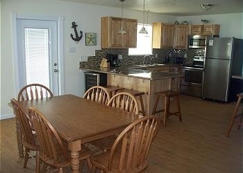 1314 Seashell Dr, Surfside Beach, TX 77541 - kitchen featuring stainless steel appliances, backsplash, light brown cabinetry, light wood-style flooring, and a breakfast bar area