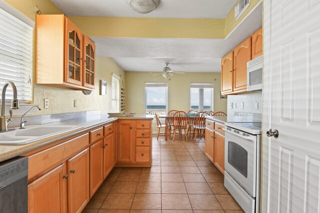 115 Southwind Dr, Surfside Beach, TX 77541 - kitchen with white appliances, light countertops, glass insert cabinets, a peninsula, and a ceiling fan