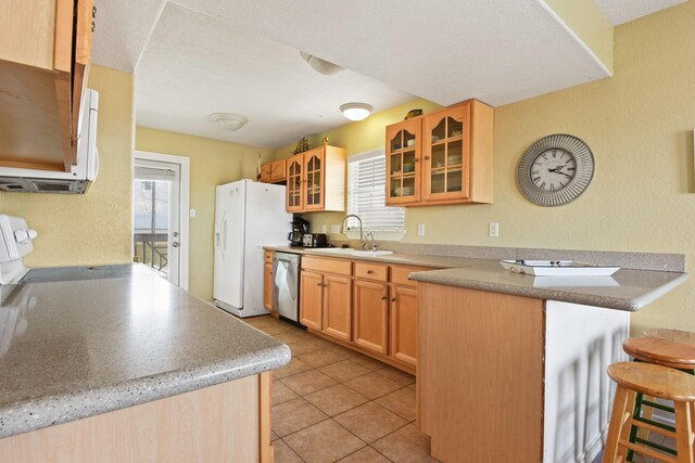 115 Southwind Dr, Surfside Beach, TX 77541 - kitchen with white appliances, glass insert cabinets, a kitchen breakfast bar, light tile patterned flooring, and a peninsula