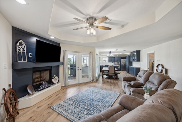 527 Caney Creek Dr, Livingston, TX 77351 - living room featuring french doors, a fireplace, light wood finished floors, ceiling fan, and a tray ceiling
