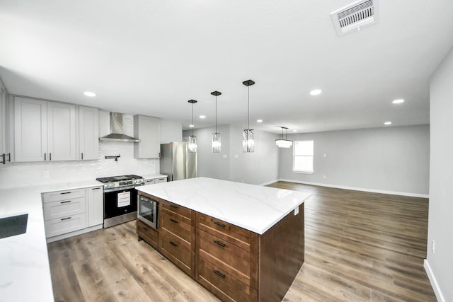 1218 Des Jardines St, Houston, TX 77023 - kitchen featuring appliances with stainless steel finishes, wall chimney exhaust hood, recessed lighting, tasteful backsplash, and light wood finished floors