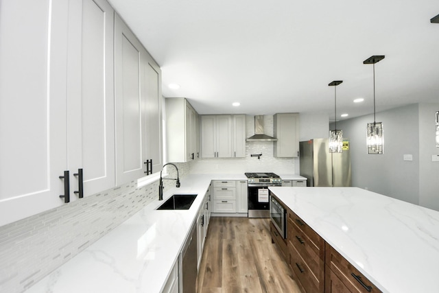 1218 Des Jardines St, Houston, TX 77023 - kitchen featuring wall chimney range hood, stainless steel appliances, tasteful backsplash, light stone countertops, and wood finished floors